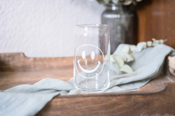 Can Longdrinkglas mit weißem Smiley, 470 ml, dekorativ auf einem Holztablett mit Stofftuch arrangiert